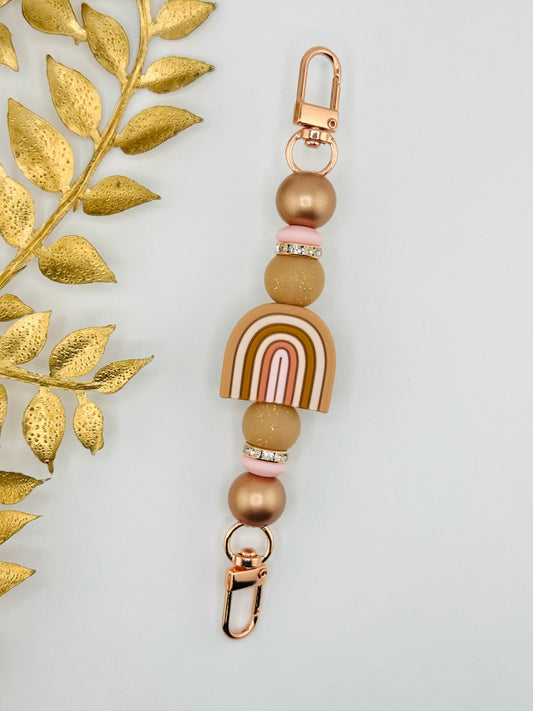 Handmade rainbow strap featuring rose gold hardware, neutral beads, and a boho rainbow focal. Works on kindle and other devices 