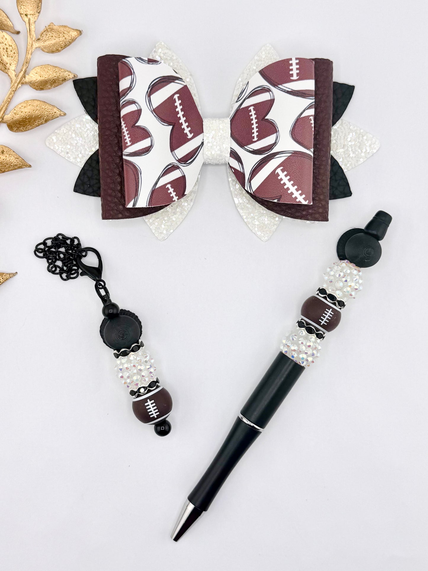 Football themed faux leather bow set with matching beaded pen and keychain charm in black, white glitter, and brown football print.