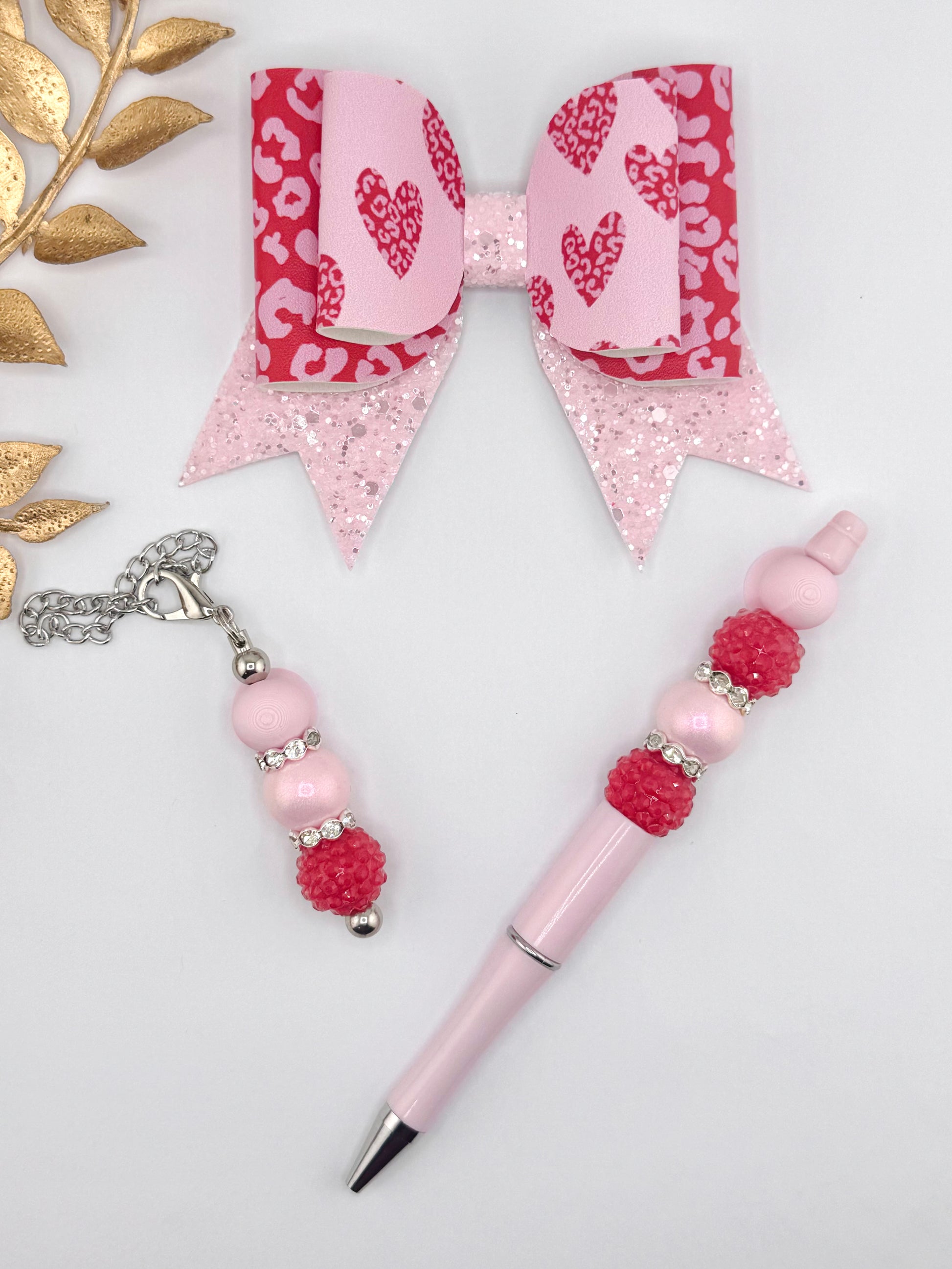 Pink leopard heart faux leather bow kit with glitter tail bow, pastel pink beaded pen, and coordinating beaded charm on a white background