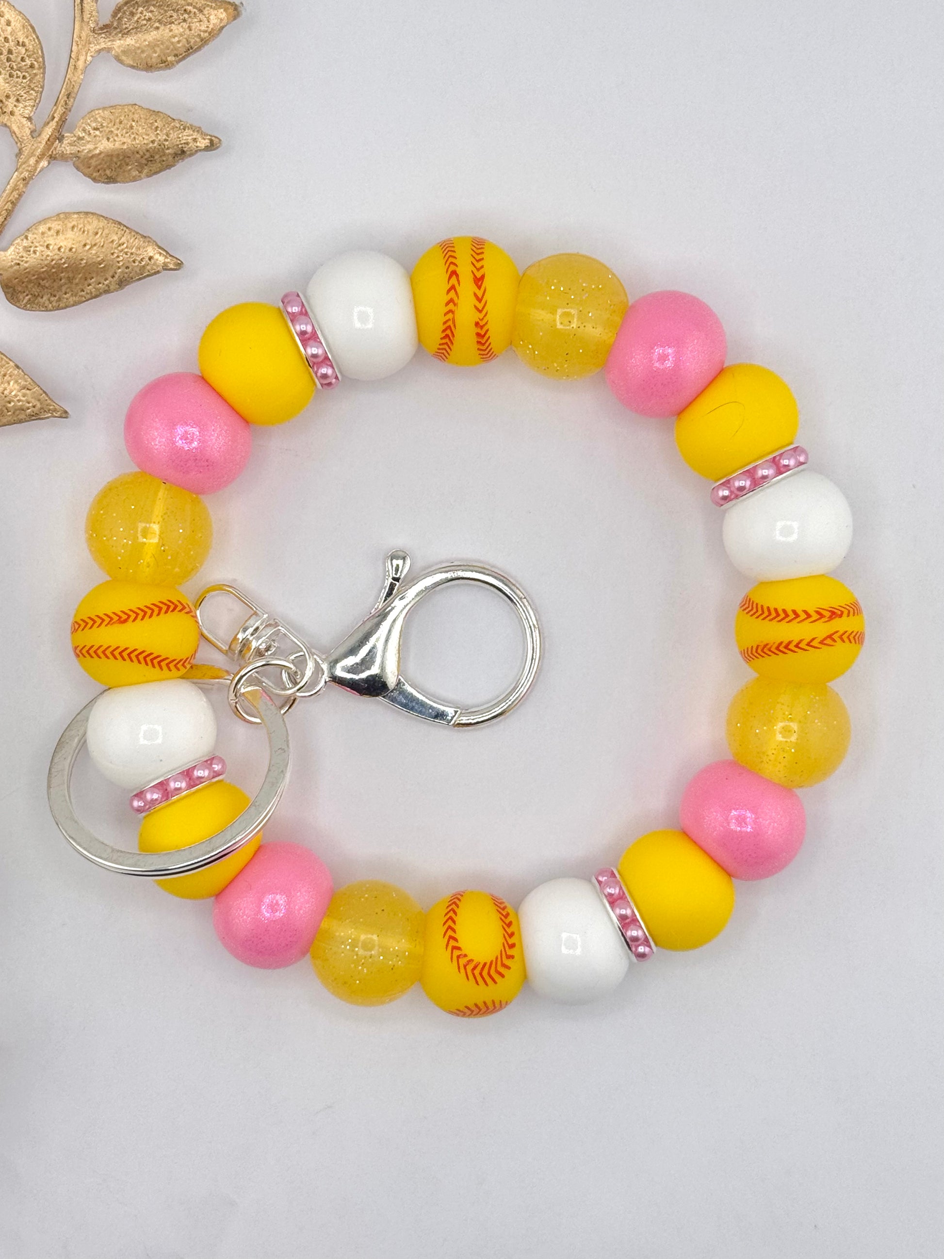Pink and yellow silicone bead keychain wristlet with softball printed beads, glitter yellow beads, and silver clasp hardware.